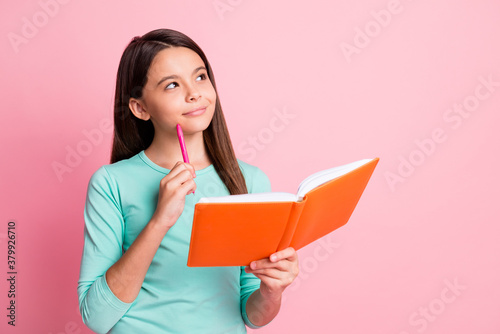 Photo of pretty sweet little clever thoughtful latin lady long hairdo arms hold orange diary pen cheekbone look up empty space wear turquoise sweatshirt isolated pink color background