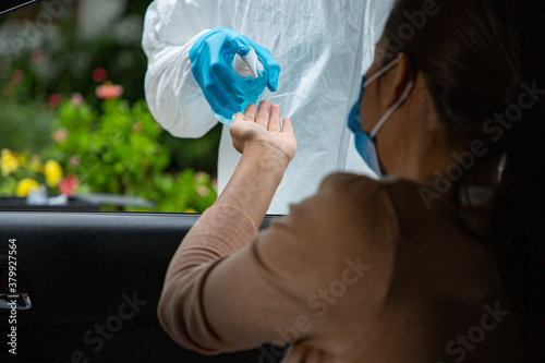 PPE medical staff press alcohol gel to driver for sanitize