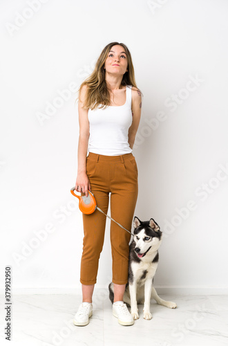 A full length young pretty woman with her dog and looking up