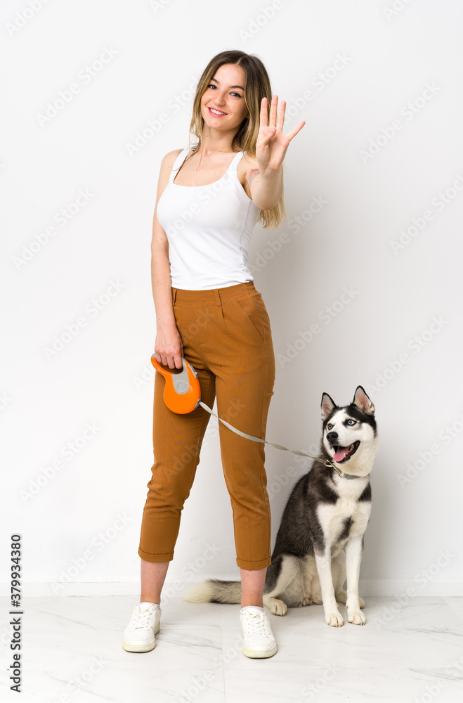 A full length young pretty woman with her dog happy and counting four with fingers