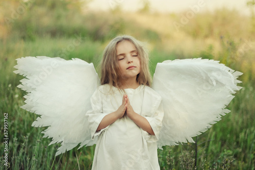 Angel girl with wings closed her eyes and prays