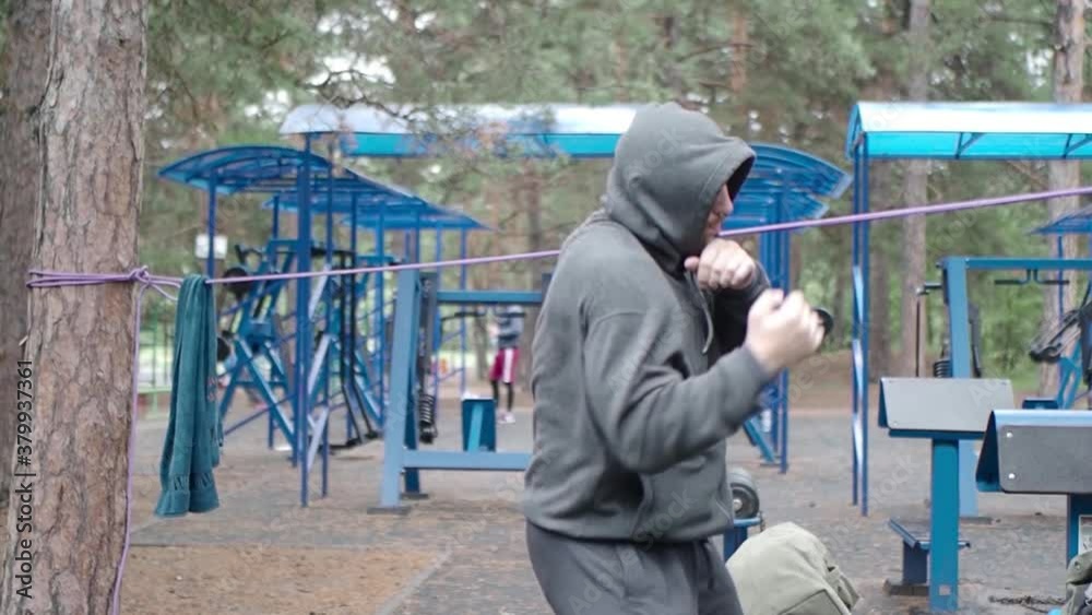 Shadowfight - boxing fighter workout in public park on workout ground. Shadowfight - boxing fighter workout in public park on workout ground.