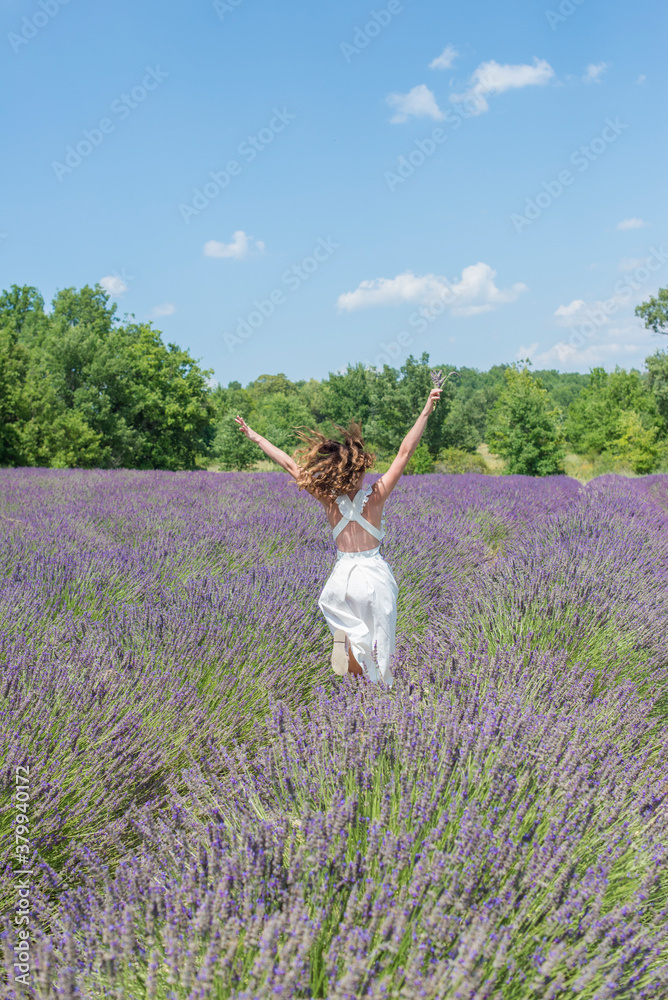 A brunette curly hair girl running in the purple field of lavender in Provence A brunette curly hair girl running in the purple field of lavender in Provence