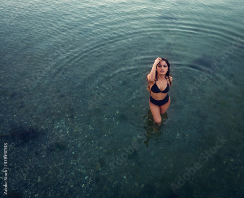 beautiful woman in black bikini on beach from drone