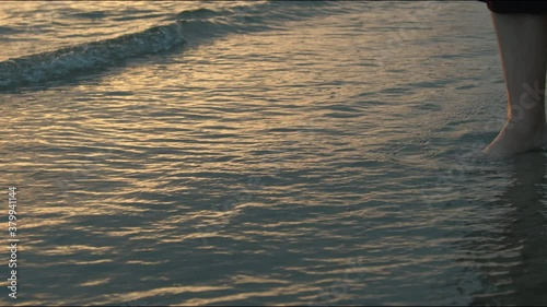 Girl walking along the baltic sea. Waves are crashing against her legs and feet. photo