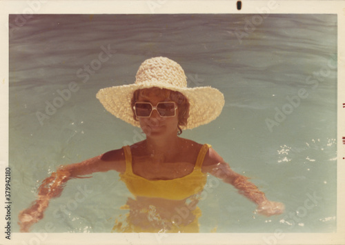 Vintage photo of a beautiful woman in a pool with a straw hat on - 1973