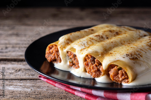 Delicious meat cannelloni pasta on rustic wooden table	 photo