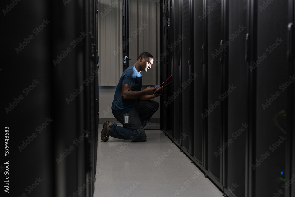 Technician's face is lit as he looks down at a digital tablet in Technician's face is lit as he looks down at a digital tablet in