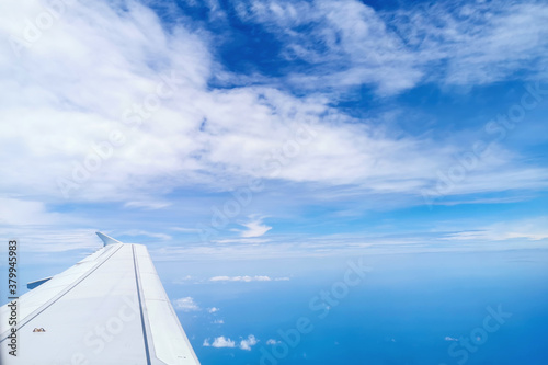 Airplane flight. Wing of an airplane flying above the golden fluffy clouds moving softly on the sky and the sun shining through the clouds with beautiful rays. © shine