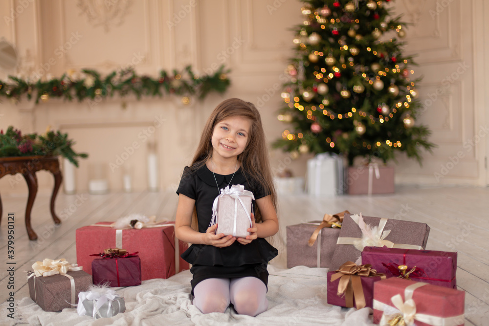 A little girl opens a Christmas present from Santa. Christmas tale. Happy childhood A little girl opens a Christmas present from Santa. Christmas tale. Happy childhood