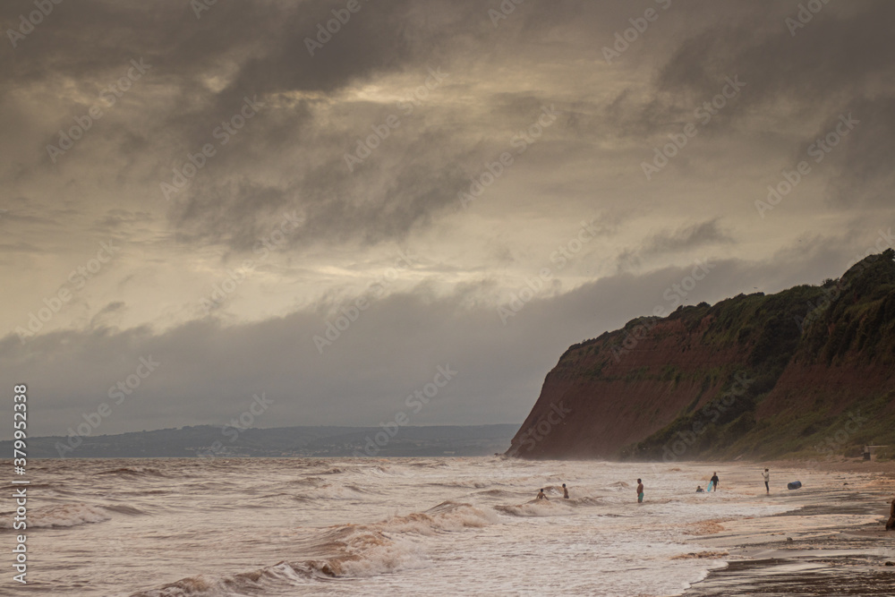 stormy clouds over the sea and children playing in the surf