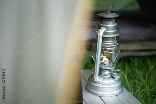 日中、芝生のテント越しに灯るオイルランタン