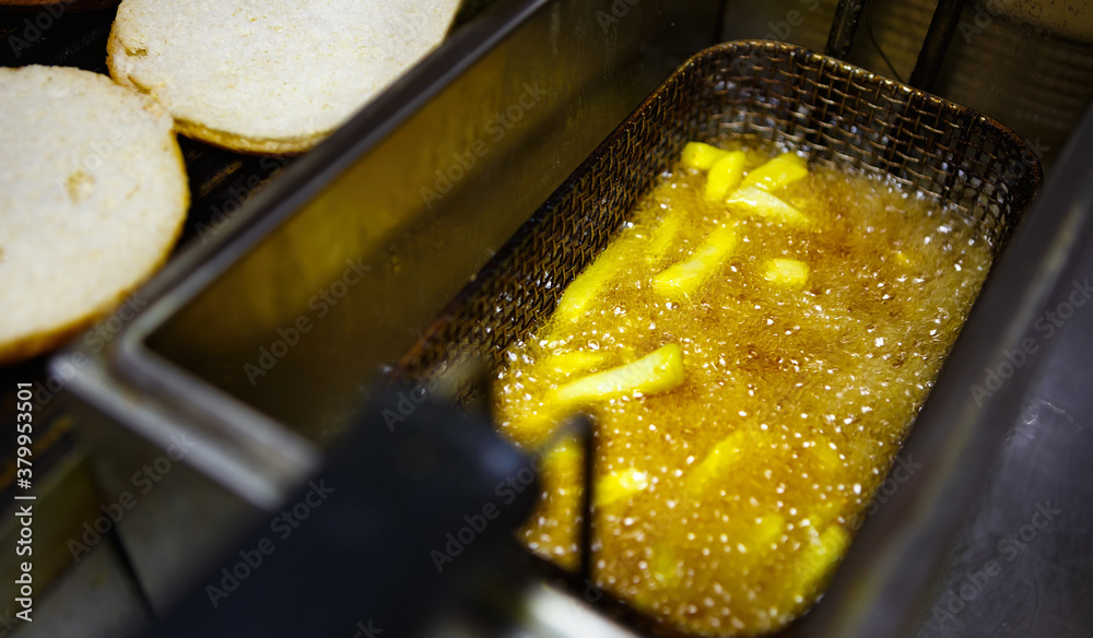 Foto de Frying French fries in deep fryer oven in hot boiling oil for