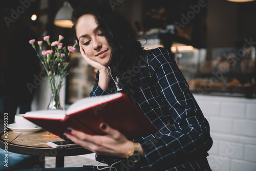 Content woman enjoying book in cafeteria photo