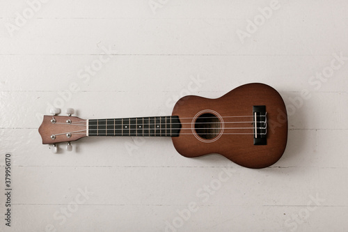 brown ukulele on white floor