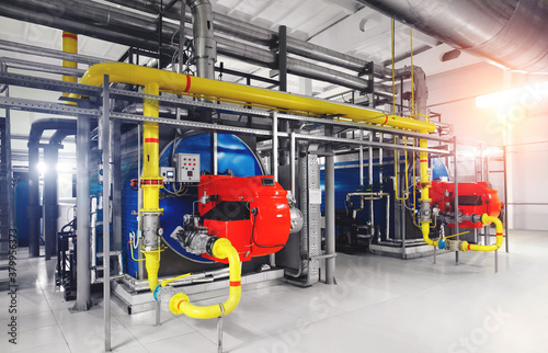 Interior of modern industrial gas boiler room with two gas boilers and pipes for supplying gas and steam. Sun flarers
