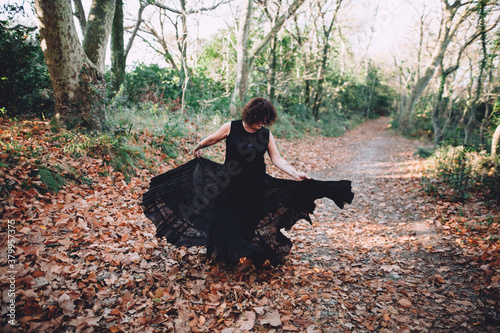 mature woman dancing with a vaporous black dress in the mountain