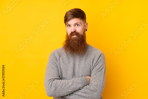 Redhead man with long beard over isolated yellow background feeling upset