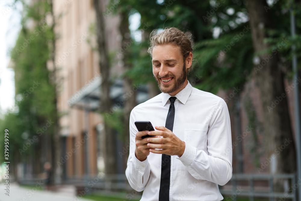 Portrait of a successful young businessman. A curly-haired man in a white shirt with a telephone against the background of a modern business center. Portrait of a successful young businessman. A curly-haired man in a white shirt with a telephone against the background of a modern business center.