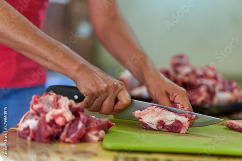 Fototapeta Naklejka Na Ścianę i Meble -  Woman's hand slicing beef on a wooden board
