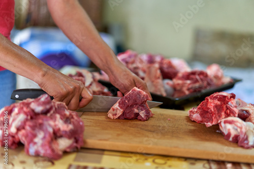 Woman's hand slicing beef on a wooden board