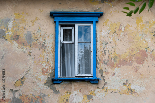 Vintage blue wooden window on house facade with old plaster