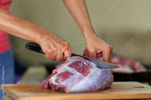 Fototapeta Naklejka Na Ścianę i Meble -  Woman's hand slicing beef on a wooden board