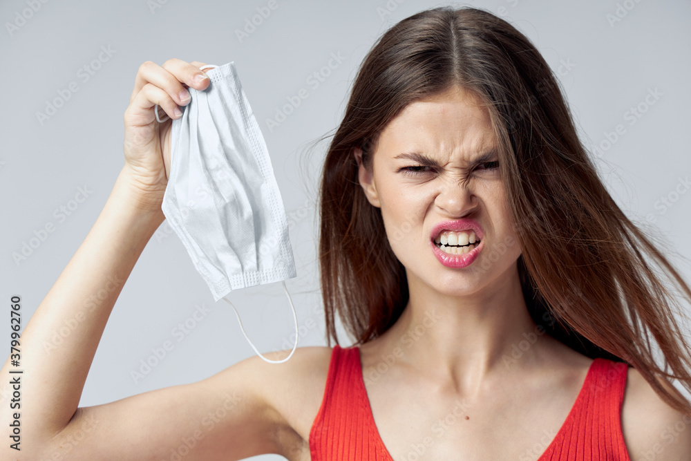 Angry woman medical mask in hand grimace. Red t-shirt Angry woman medical mask in hand grimace. Red t-shirt