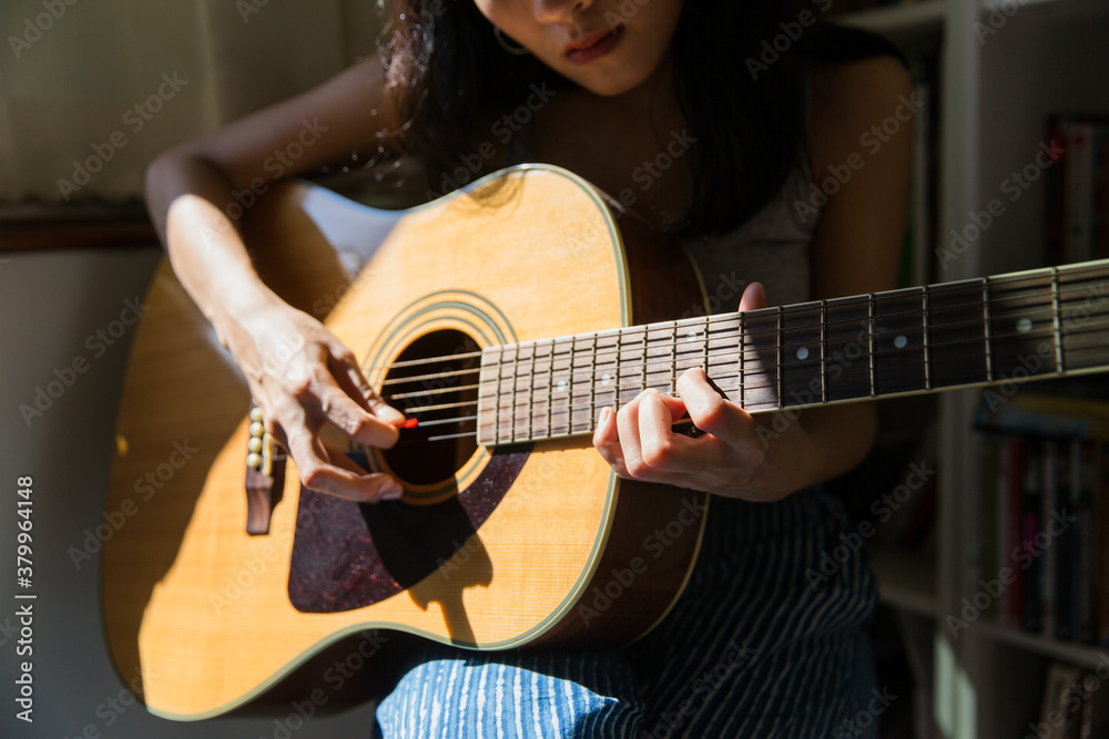 Beautiful Asian woman playing guitar at home Beautiful Asian woman playing guitar at home