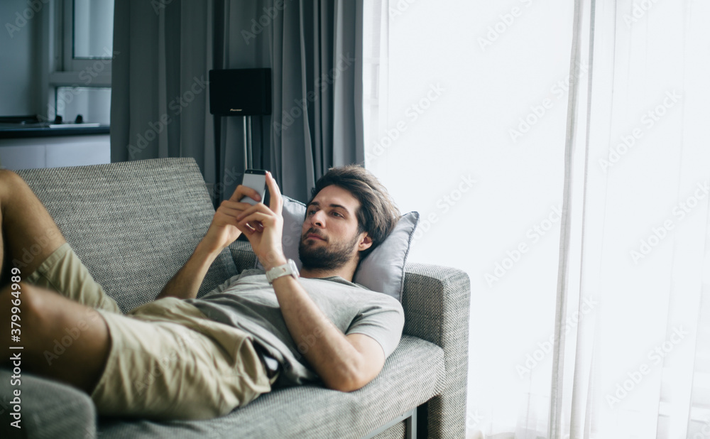 Young man sitting on the sofa texting on the phone Young man sitting on the sofa texting on the phone