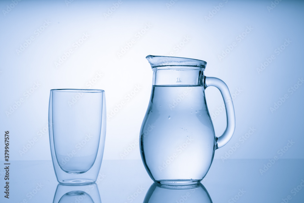 Pitcher with drinking water and a glass with a drink, blue tone Pitcher with drinking water and a glass with a drink, blue tone
