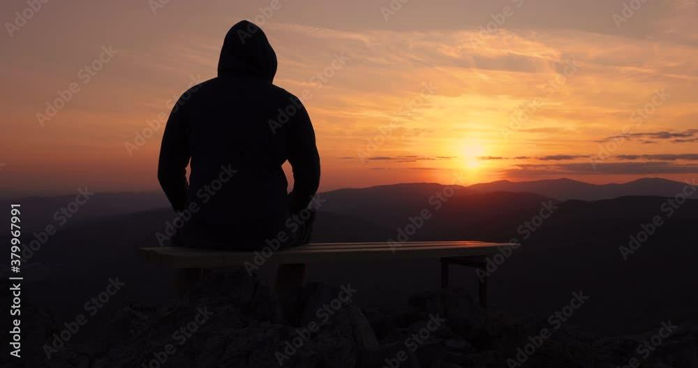 Man looking toward burning sunset sky and panoramic view of mountain hills