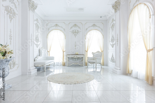 luxury royal posh interior in baroque style. very bright, light and white hall with expensive oldstyle furniture. large windows and stucco ornament decorations on the walls © 4595886