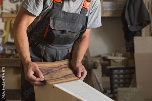 Carpenter aplying veneer to a piece of furniture