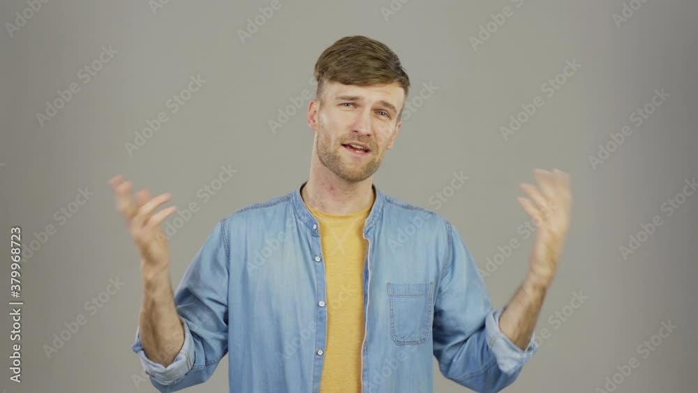 Waist up studio portrait of handsome guy looking at camera, speaking cheerfully advertising his service and saying goodbye against grey background Waist up studio portrait of handsome guy looking at camera, speaking cheerfully advertising his service and saying goodbye against grey background