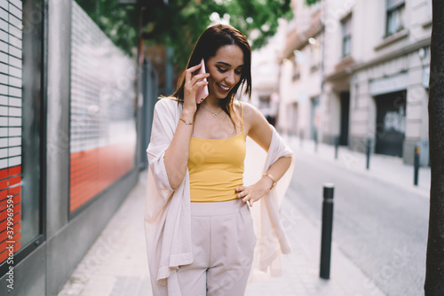 Happy woman walking on street and speaking on phone