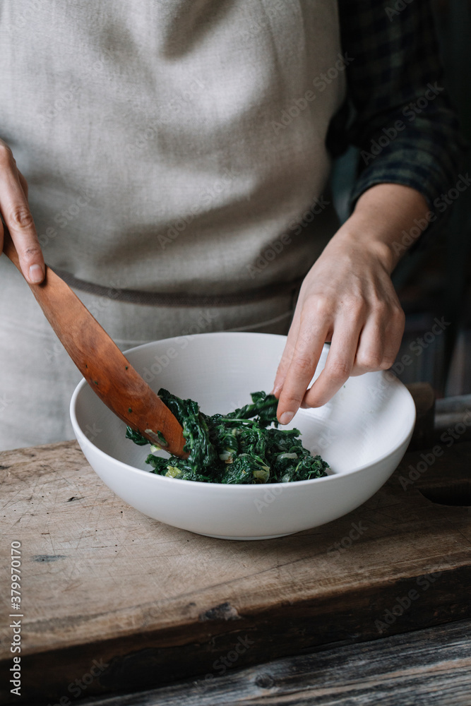 Person preparing stuffing for spanakopita