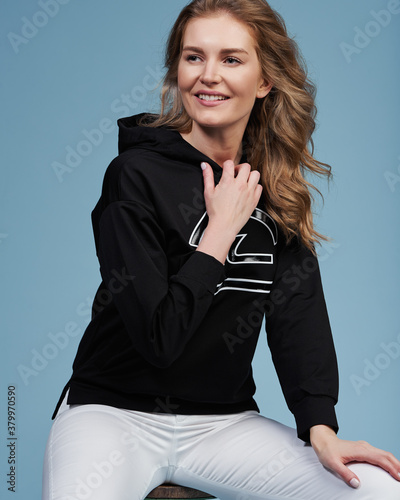 Young beautiful blonde model in fashionable clothes on a blue background. Studio fashion photography