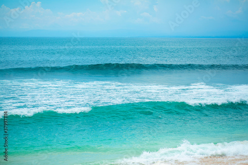 An ideal tropical sandy beach for surfing on the ocean. Beautiful clear turquoise water and waves.