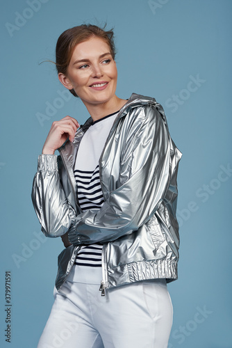 Young beautiful blonde model in fashionable clothes on a blue background. Studio fashion photography