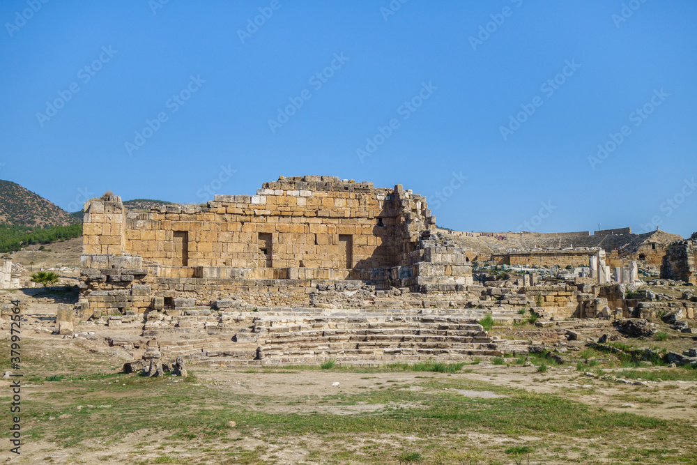 Ruins of Apollo temple in ancient city Hierapolis, Pamukkale, Turkey. Remains of Ploutonion on right side. Also there's antique theater on background. All city objects included in UNESCO List