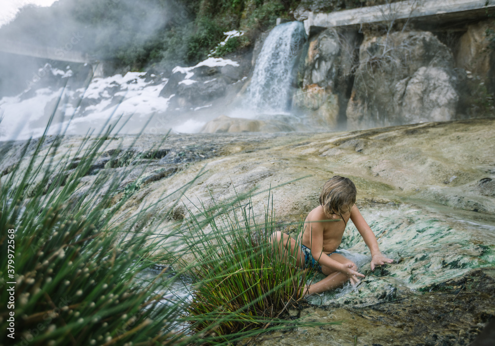 toddler playing in natural hot springs outdoors in winter