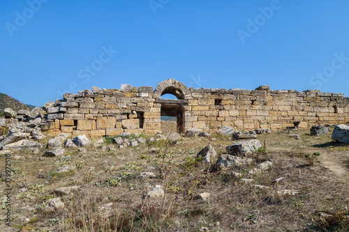 Gymnasium or antique school in ancient city Hierapolis, Pamukkale, Turkey. There are remains of gates with arch & walls. City included in UNESCO World Heritage List