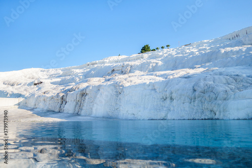 Natural travertine formations & its reflections in pool, Pamukkale, Turkey. White rocks seem like snow, but created by geothermal mineral water containing calcium carbonate. Site is included in UNESCO