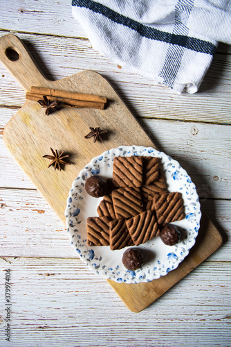 Tasty chocolate cookies and chocolates on a wooden platter on a background