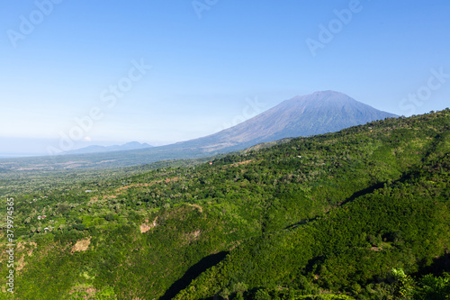Bali island landscape. Beautiful mountains covered by green jungle. Agung volcano on clear day. Sunny day at Bali island, Indonesia. With space for text.