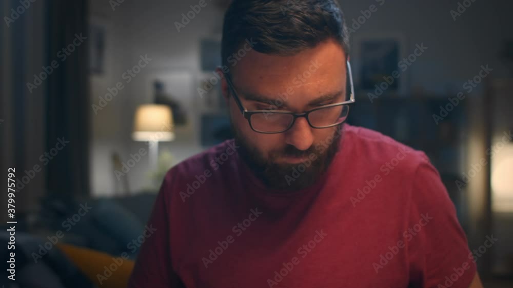 Man working with laptop and papers at home in living room