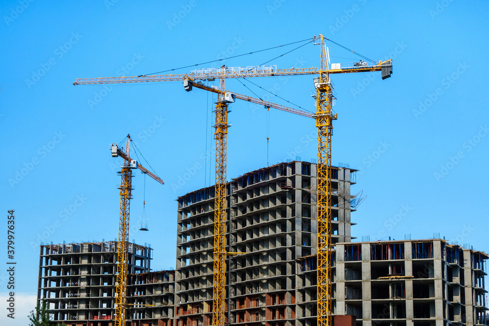 Complex of new high rise buildings under construction. Three tower cranes are working nearby.