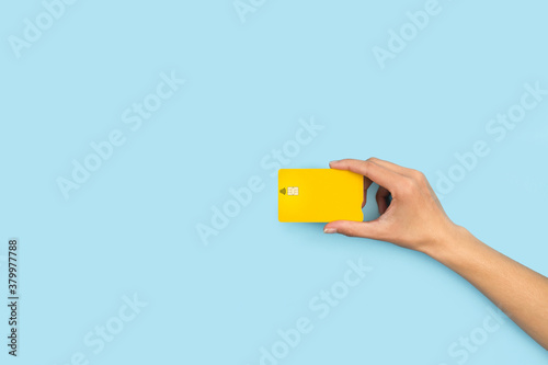 Quadro su tela Mano sosteniendo una tarjeta con chip de crédito en un fondo celeste liso y aislado