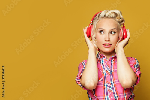 Portrait of pin-up woman with headphones on colorful yellow background